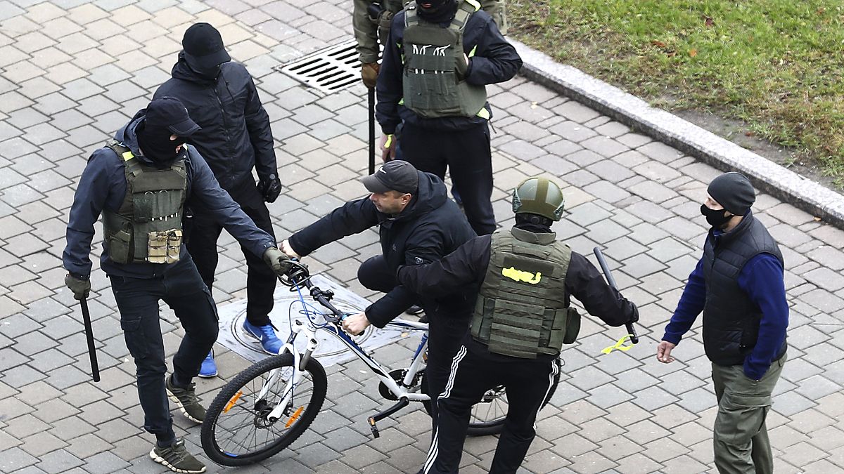 Ein Demonstrant in Minsk wird am Sonntag von maskierten Sicherheitskräften in die Zange genommen