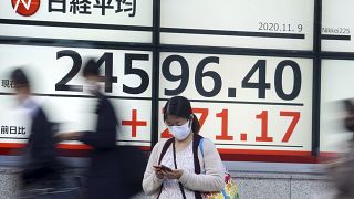 Una mujer delante de un panel con el índice Nikkei en Tokio, Japón