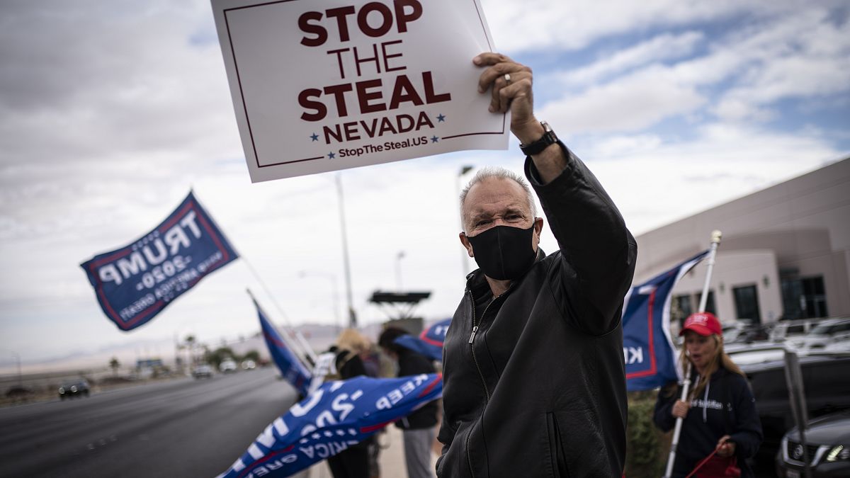 Supporters of President Donald Trump hold signs as they stand outside of the Clark County Elections Department in North Las Vegas, Nev. Saturday, Nov. 7, 2020.