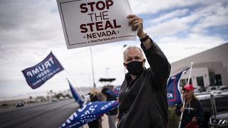 Supporters of President Donald Trump hold signs as they stand outside of the Clark County Elections Department in North Las Vegas, Nev. Saturday, Nov. 7, 2020.