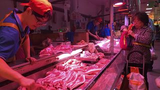 FILE - Sept. 11, 2019, a clerk stacks cuts of pork at a meat market in Beijing.