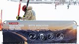 A skier prepares his skis next to the covid-19 safety instruction sign at Pitztal glacier, Austria