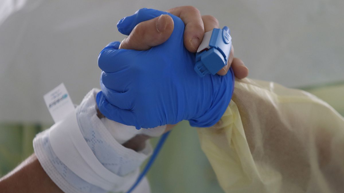 Therapeutin Catia Jesus hält die Hand einer Covid-Patientin auf der Intensivstation der Santa-Maria-Klinik in Lissabon