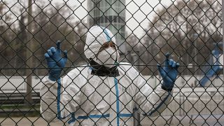 Медицинский работник в защитном костюме ожидает у пункта сортировки, который был создан для снижения нагрузки на больницы после вспышки заболевания COVID-19 в Италии.