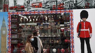 Shoppers walk past a shop window in Oxford Street, London, Tuesday, Oct. 13, 2020.