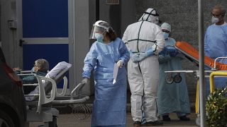 A paramedic carries a patient outside the first aid area of the Cardarelli hospital in Naples, Italy, Friday, Nov. 13, 2020