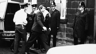 Peter William Sutcliffe (blanket on head) in Dewsbury in February 1981, where at the Magistrates Court he was committed in custody for trial on 13 counts of murder. 
