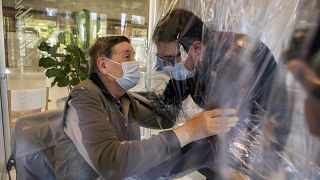 Relatives at a nursing home in Italy hug each other through a plastic film screen to avoid contracting COVID-19