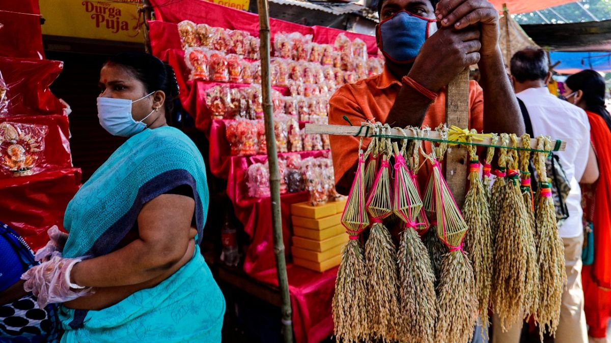 A man wearing a face mask sells sheaves of rice used to perform rituals during Diwali, the Hindu festival of lights, in Kolkata, India, Saturday, Nov. 14, 2020.  