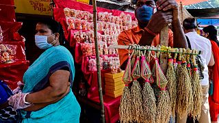 A man wearing a face mask sells sheaves of rice used to perform rituals during Diwali, the Hindu festival of lights, in Kolkata, India, Saturday, Nov. 14, 2020.