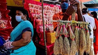 A man wearing a face mask sells sheaves of rice used to perform rituals during Diwali, the Hindu festival of lights, in Kolkata, India, Saturday, Nov. 14, 2020.  