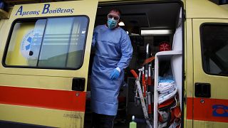 A paramedic wearing a suit to protect against coronavirus, closes the door of an ambulance at Evangelismos hospital in Athens