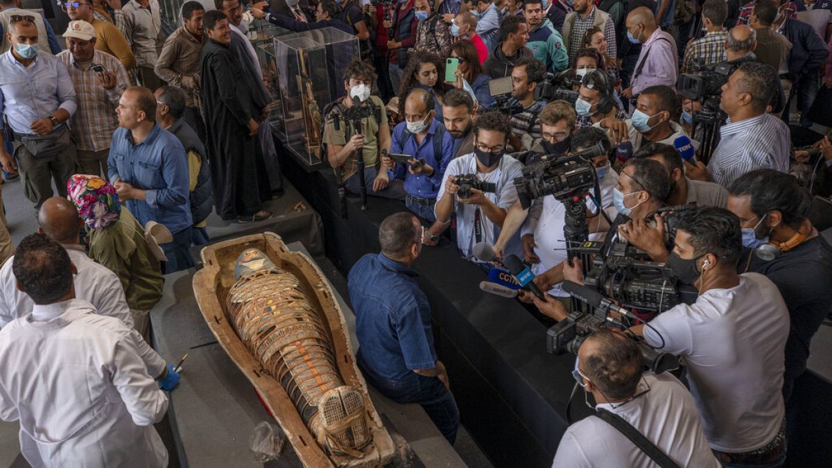 Journalists gather around an ancient sarcophagus more than 2500 years old, discovered in a vast necropolis.