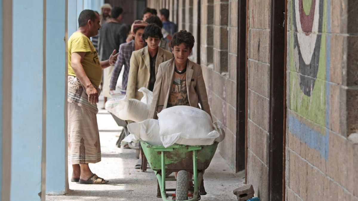 In this Aug. 25, 2019, file photo, displaced Yemenis receive food supplies provided by the World Food Programme, at a school in Sanaa, Yemen. 