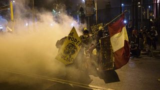 Protesters take refuge from tear gas launched by police to disperse protesters refusing to recognize Peru's new government, in Lima, Saturday, Nov. 14, 2020. 