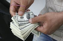 شمارش اسکناس‌های دلار توسز یک فروشنده ارز در بازار تهران