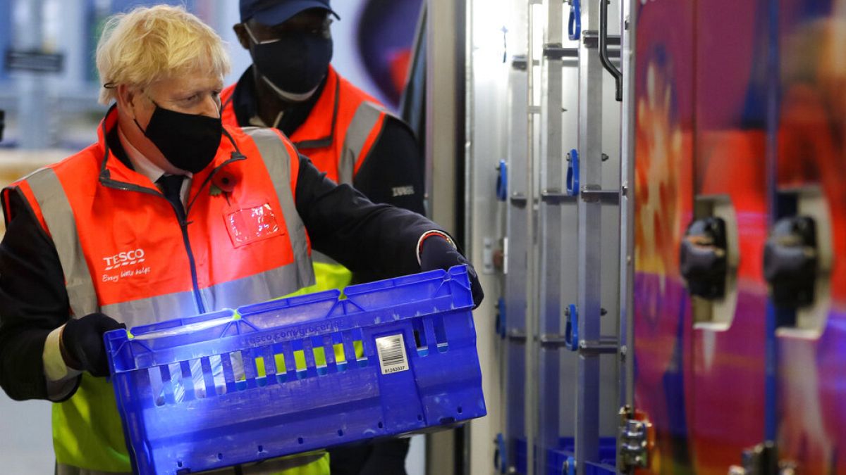 Britain's Prime Minister Boris Johnson loads a delivery van with a basket of shopping during a visit to a tesco.com distribution centre in London, Wednesday, Nov. 11, 2020. 