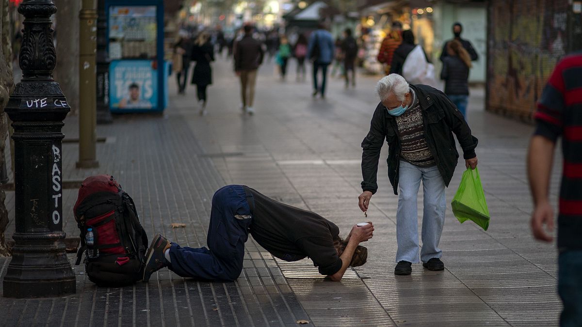 Un passant donne de l'argent à un mendiant sur les Remblas à Barcelone, le 12 novembre 2020