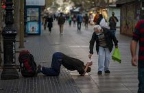 Un passant donne de l'argent à un mendiant sur les Remblas à Barcelone, le 12 novembre 2020