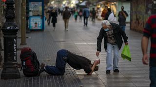 Un passant donne de l'argent à un mendiant sur les Remblas à Barcelone, le 12 novembre 2020
