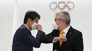 Former Japan's Prime Minister Shinzo Abe, left, and Thomas Bach, President of the International Olympic Committee (IOC), bump elbows in Tokyo