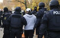 Police officers escort a person for an identity check in Berlin, Germany, Tuesday, Nov. 17, 2020.