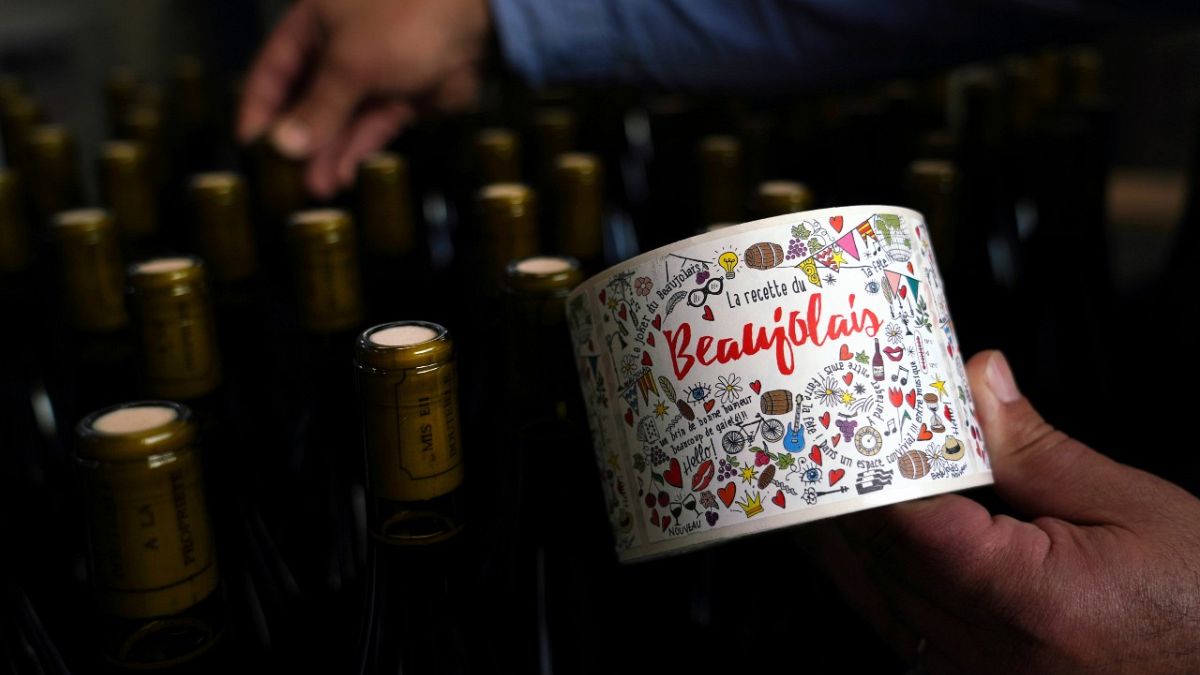 Tuesday, Nov. 12, 2019, a man picks a bottle of Beaujolais Nouveau in the Vinescence cellar in Saint Jean d'Ardieres, in the Beaujolais region