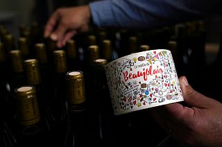 Tuesday, Nov. 12, 2019, a man picks a bottle of Beaujolais Nouveau in the Vinescence cellar in Saint Jean d'Ardieres, in the Beaujolais region