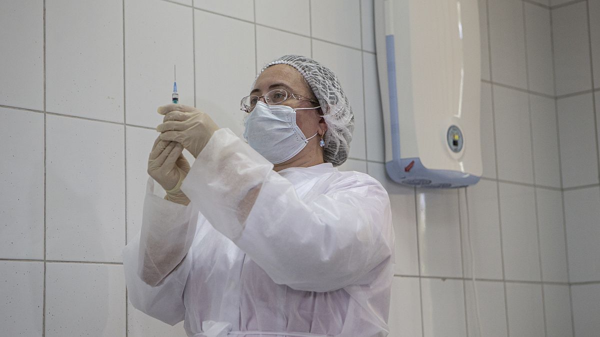 Медсестра готовится к введению экспериментальной вакцины или плацебо волонтёру
