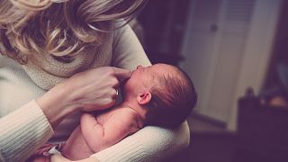 A woman holds a newborn baby.