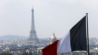 The French flag above the skyline of the French capital with the Eiffel Tower.