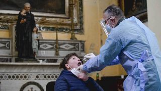 A medical operator performs COVID-19 test swabs in the Church of San Severo Outside the Walls, in the heart of Naples, Italy, Wednesday, Nov. 18, 2020.