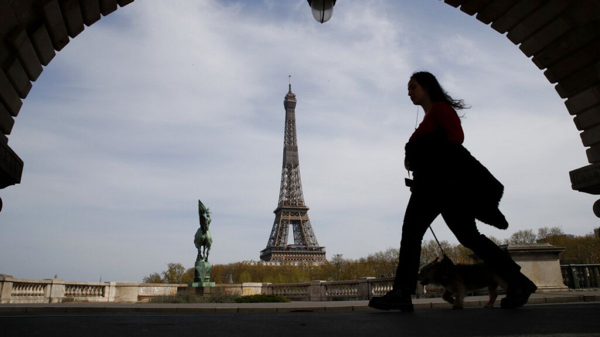 Archivo. Una mujer pasea a su perro cerca de laTorre Eiffel de París.