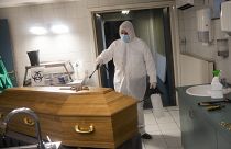 A worker, wearing a full protective equipment, disinfects the casket of someone who died of coronavirus COVID-19 at a funeral home in Charleroi, Belgium, Nov 17, 2020.