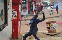 A person prepares to throw a rock during clashes between security forces and protesters supporting opposition presidential candidate Bobi Wine