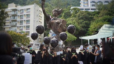 Students from the Chinese University of Hong Kong (CUHK) hold black balloons and placards as they gather at the statue of the "Goddess of Democracy"