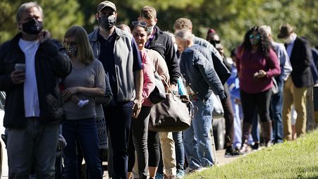 Voters brave a bright sun as they wait to cast their ballots in Mississippi, US.