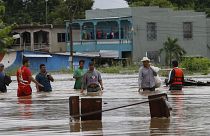 Hombres caminan por una calle inundada después del paso del huracán Iota en La Lima, Honduras