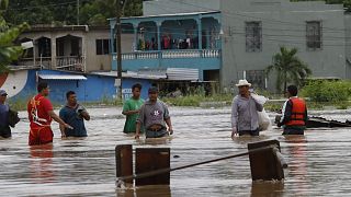 Hombres caminan por una calle inundada después del paso del huracán Iota en La Lima, Honduras
