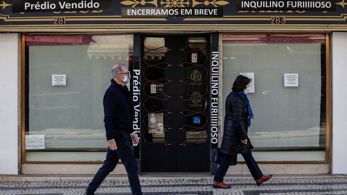 Traseuntes passam por uma loja fechada na zona da baixa pombalina de Lisboa