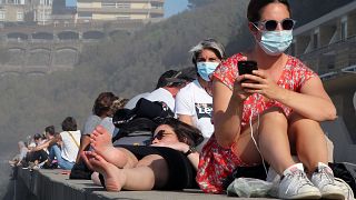 People sunbathe near the Atlantic ocean in Biarritz, southwestern France, Sunday, Nov. 1, 2020.