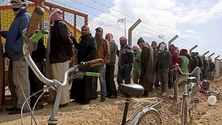 Syrian refugees line up to register their names at an employment office, at the Azraq Refugee Camp in Jordan.