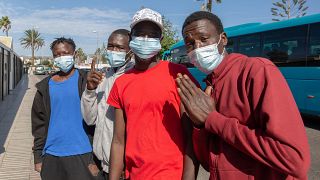 Malian migrants gesture as they wait to be transferred to their accommodation after arriving by boat on the Canary Island of Gran Canaria on November 23, 2020