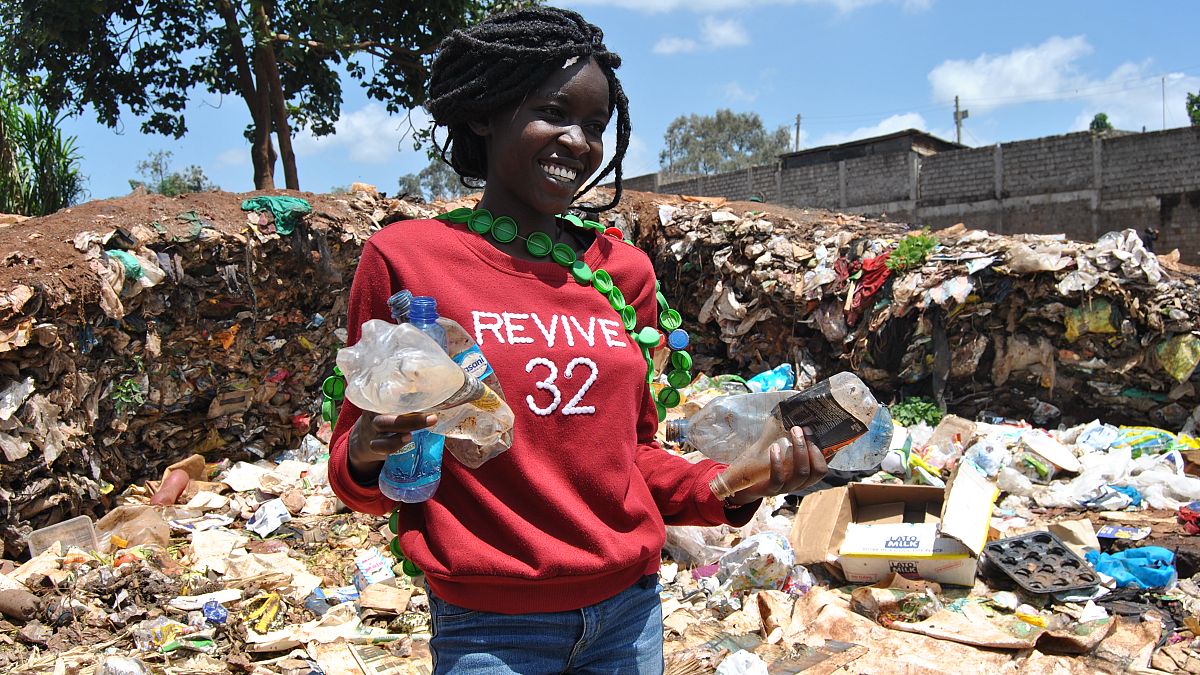 Kibera's Mev Adongo holds up plastic bottles she has picked from the trash near the railway line.