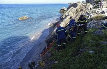 Firefighters retrieve the body of a migrant from the beach after the boat partially sank near the Greek island of Rhodes.