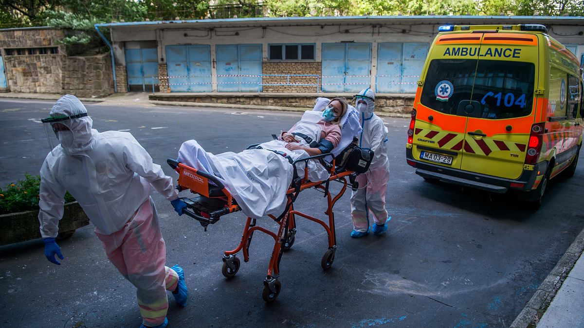 Védőruhába öltözött mentők egy koronavírussal fertőzött beteg szerepét eljátszó statisztát hoznak hordágyon 