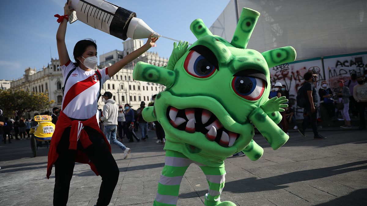 Koronavírus elleni védőoltásnak és koronavírusnak öltözött színészek egy tüntetésen Limában