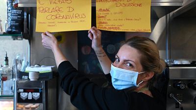  "Feeling Bar" في ضواحي روما صاحبة الحانة كريستينا ماتيولي وهي تقف بجانب لافتة كتب عليها "ممنوع الحديث عن فيروس كورونا"