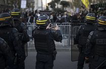 A French riot police officer photographs protesters with his phone during a demonstration in Marseille, southern France, Saturday, Nov. 21, 2020.