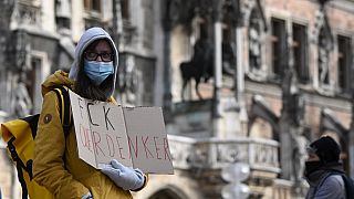 A woman protests with a sign against an anti Covid-19 restrictions' protest in front of the city hall in Munich, southern Germany, on November 16 